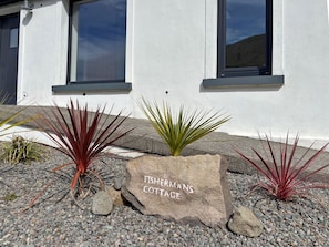 Un bâtiment blanc avec une enseigne indiquant « FISHERMANS COTTAGE » à l’avant.