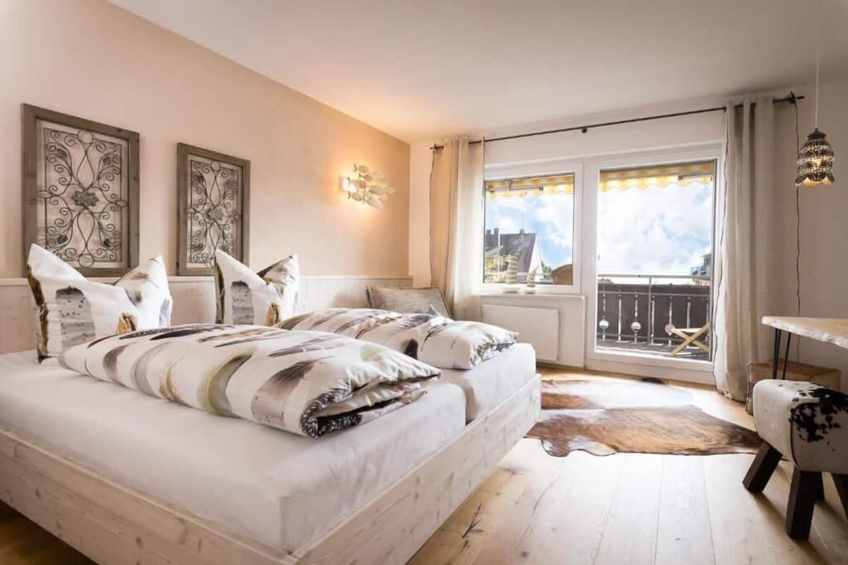 A bedroom with a large bed, a view of the city, and a balcony.
