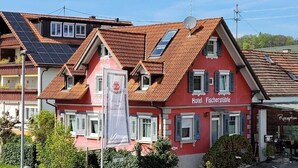 A red building with a sign 'Hotel Fischerstüble' and a solar panel on the roof.