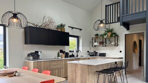 Une cuisine moderne avec des meubles noirs, un îlot central en bois et des chaises rouges.