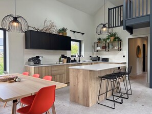 A modern kitchen with black cabinets, a wooden island, and red chairs. - Cottage 505 - Roundstone - sleeps 8 guests  in 4 bedrooms (Roundstone)