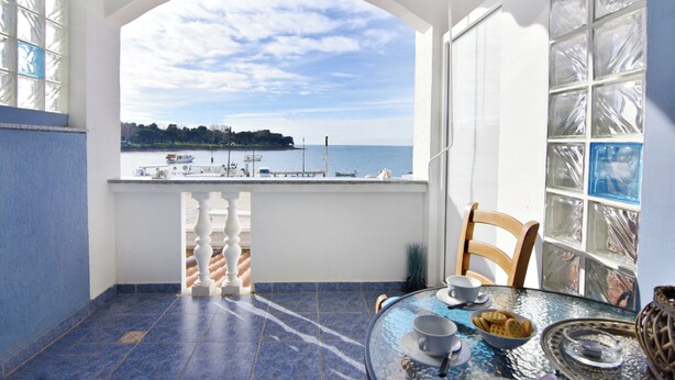 Un balcon avec vue sur la mer, une table avec un plateau et une chaise.