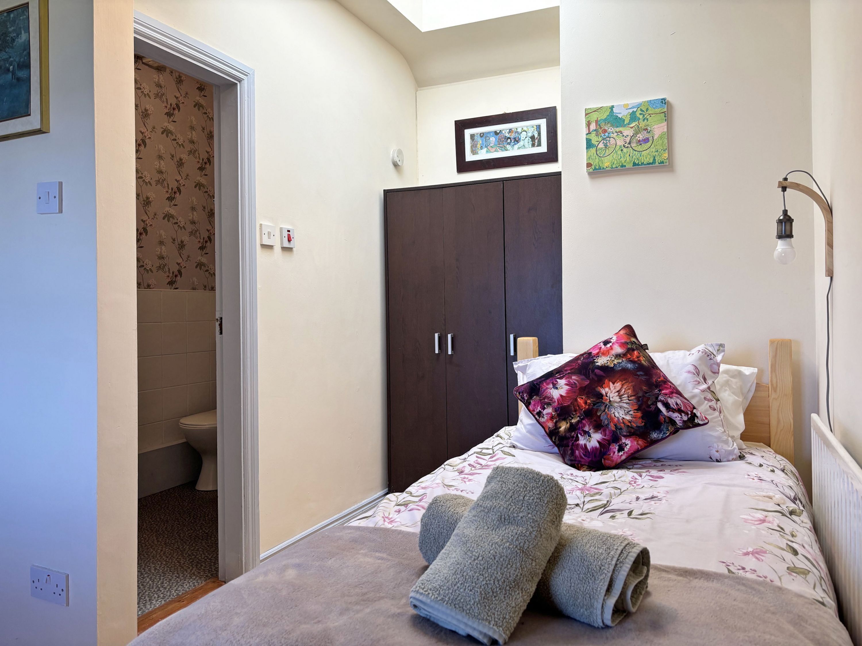 Une chambre à coucher comprenant un lit, une armoire, une salle de bain et un luminaire.