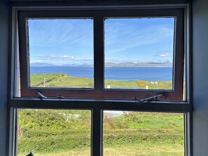A window with a view of a grassy landscape and a body of water. - Cottage 507 - Renvyle - sleeps 6 guests  in 3 bedrooms (Renvyle)