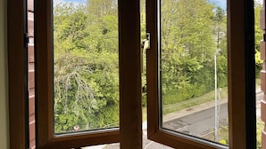 A window with a view of a building with a clock tower, surrounded by trees and a road. - Apartment 514 - Clifden - sleeps 6 guests  in 3 bedrooms (Clifden)