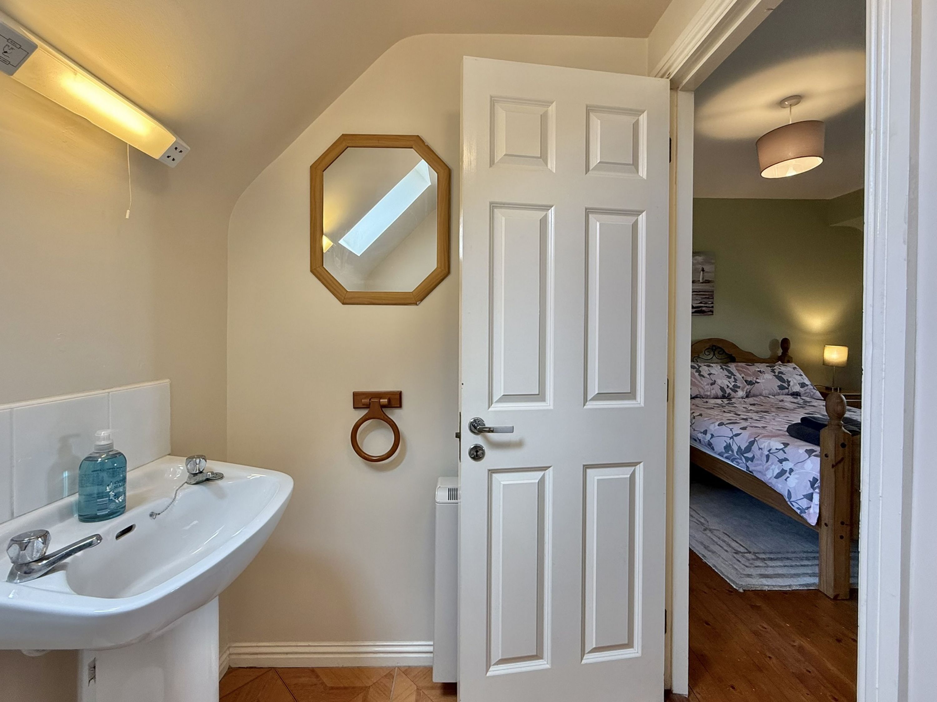 A bathroom with a white sink, a mirror, and a toilet.
