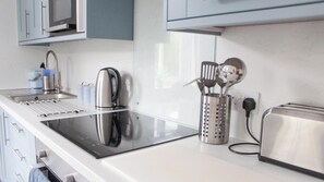 A modern kitchen with a built-in induction cooktop, a kettle, a toaster, and a utensil holder. - Allerdale (Torquay)