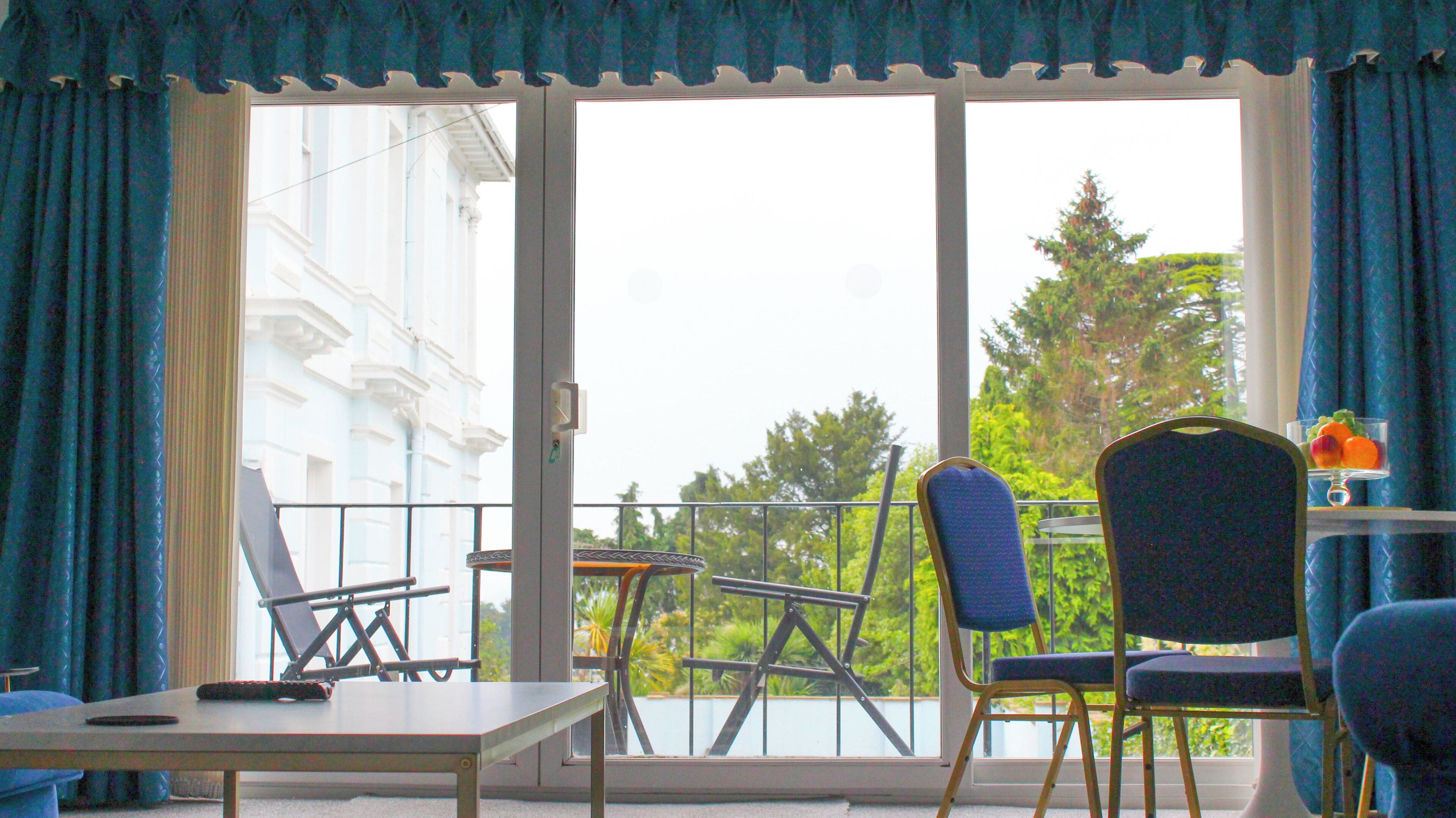 A balcony with a table, chairs, and a remote control.