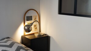 Een slaapkamer met een bed, nachtkastje, lamp, een ingelijst schilderij en een tv aan de muur.