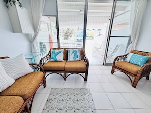 A room with wicker furniture, a patterned rug, and a view through glass doors.