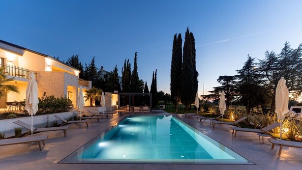 A rectangular swimming pool with lounge chairs and umbrellas, surrounded by tall trees and a building with a balcony. - La Residenza Vila apartment I for 6 guest's 1,5 km from sea (Poreč)