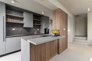 Eine moderne Küche mit Marmor-Spritzschutz, Holzschränken und einer integrierten Kochinsel.