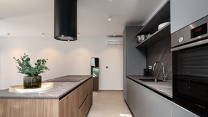 A modern kitchen with a marble countertop, wooden cabinets, a black range hood, and a stainless steel oven. - La Residenza Vila Apartment III for 6 guests, 1.5 km from the sea (Poreč)