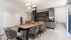 A modern kitchen with a central island, grey upholstered chairs, and a contemporary pendant light. - La Residenza Vila Apartment III for 6 guests, 1.5 km from the sea (Poreč)