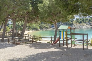 Ein Spielplatz mit Rutsche, umgeben von Bäumen und einem Strand.