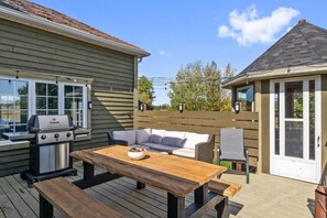 A deck with a grill, a wooden table, and a sofa. - Riverview Countryside Farmhouse, King bed Spa Bath (Paroisse de Saint-Louis)