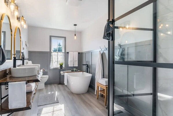 A modern bathroom with a freestanding bathtub, a large mirror, and a window. - Riverview Countryside Farmhouse, King bed Spa Bath (Paroisse de Saint-Louis)