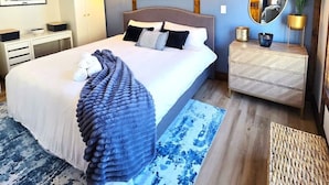 Ein Schlafzimmer mit einem Bett, Nachttischen, einer Kommode, einem Spiegel und einer Klimaanlage.