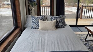 Ein Schlafzimmer mit einem großen Bett, einem Fenster und Blick ins Freie.