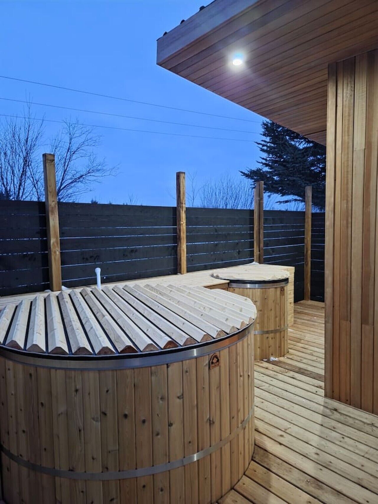 A wooden deck with a hot tub and a covered seating area.