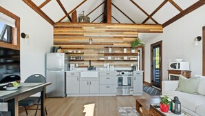 A modern kitchen with wooden beams, a dining area with a table and chairs, and a living area with a sofa and a coffee table.