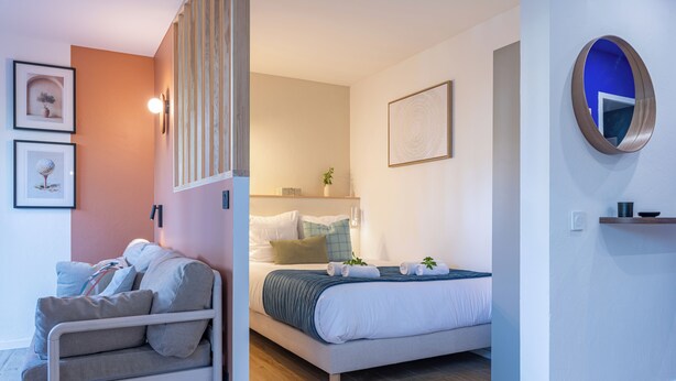 Quarto moderno com cama, sofá e uma mesinha.