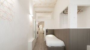 Un couloir menant à une chambre à coucher équipée d’un lit, d’une armoire et d’un portant à vêtements.