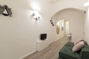 Ein modernes Wohnzimmer mit Flachbildfernseher, einem grünen Sofa und Wanddekorationen.