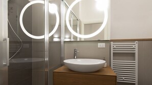 Une salle de bain moderne avec une douche à parois de verre, un meuble-lavabo en bois avec un lavabo blanc et un porte-serviettes blanc.