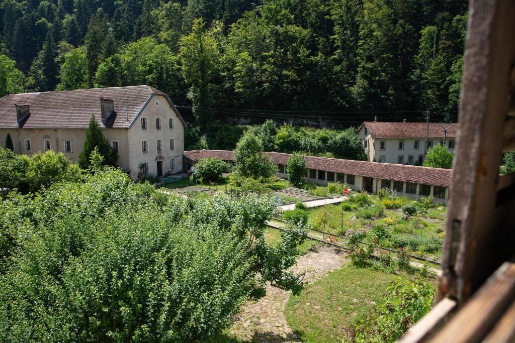 A building with a sloped roof, surrounded by greenery and trees.