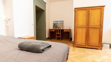 Um quarto com cama, escrivaninha e guarda-roupa.