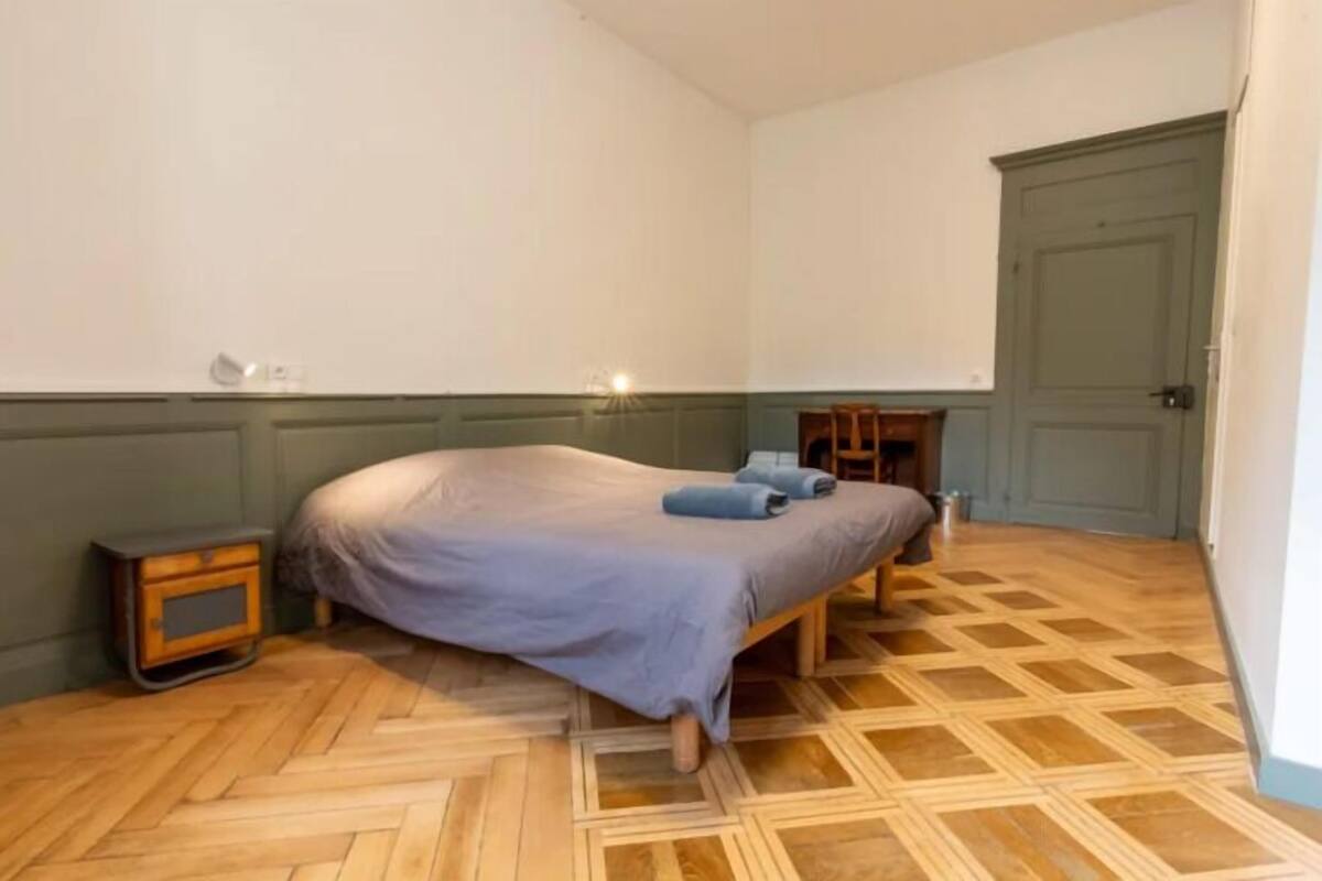 Une chambre à coucher avec un lit, une table de chevet, une chaise et une porte.