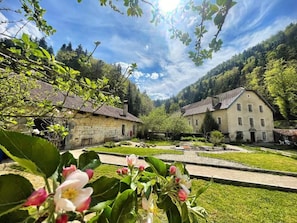 A courtyard with stone buildings, a paved walkway, and lush greenery.