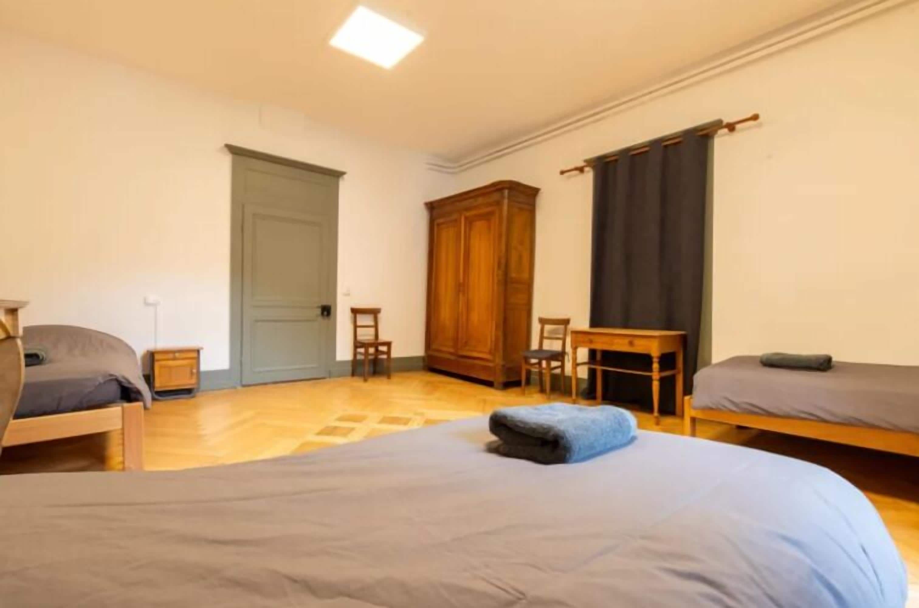 Una habitació amb dos llits, un armari de fusta, un escriptori i una cadira.
