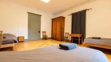 Una habitació amb dos llits, un armari de fusta, un escriptori i una cadira.