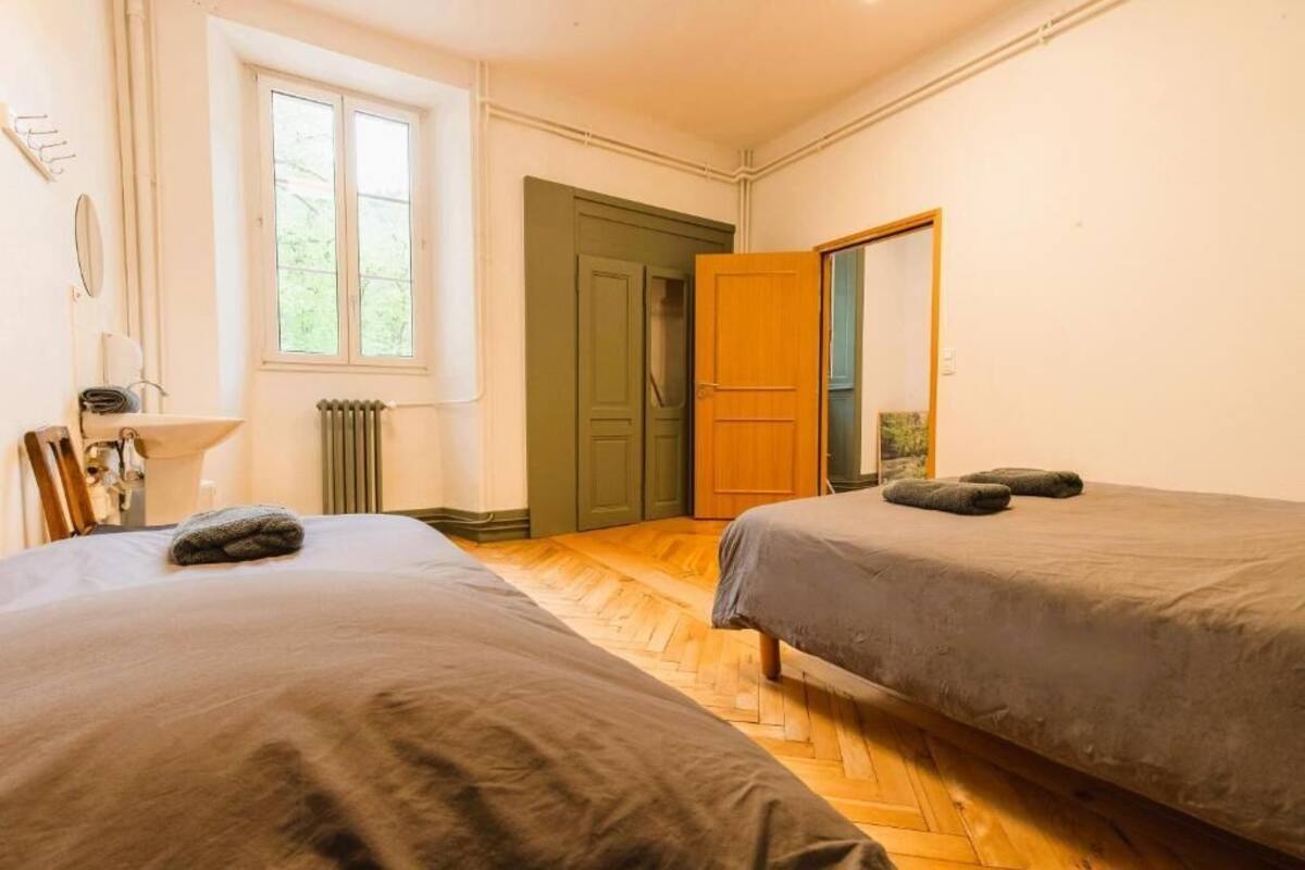 Une pièce avec deux lits, un radiateur, une fenêtre et une porte.