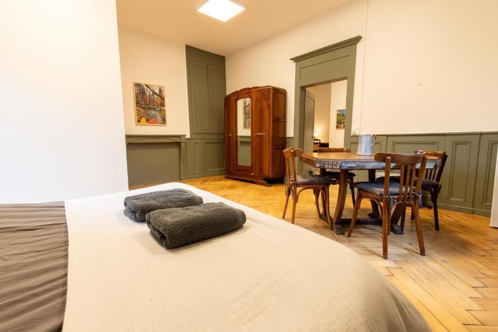 Ein Zimmer mit einem Bett, einem Tisch mit Stühlen, einem Spiegel und einem Schrank.