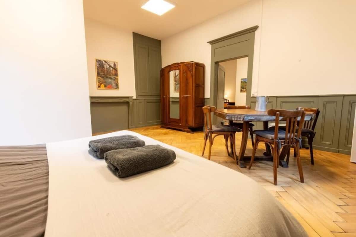 Une pièce comprenant un lit, une table avec des chaises, un miroir et un meuble.