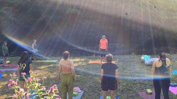 A group of people on outdoor exercise mats in a natural setting.