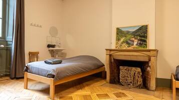 Una habitación con cama, chimenea, un cuadro y una ventana con cortinas.