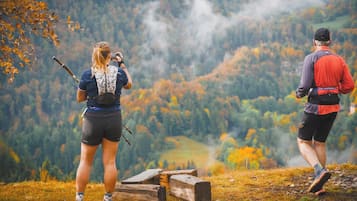 Twee mensen wandelen in een bergachtig gebied met herfstkleuren.