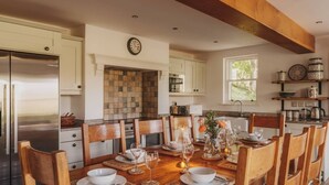 A dining area with a wooden table set for six, surrounded by wooden chairs.