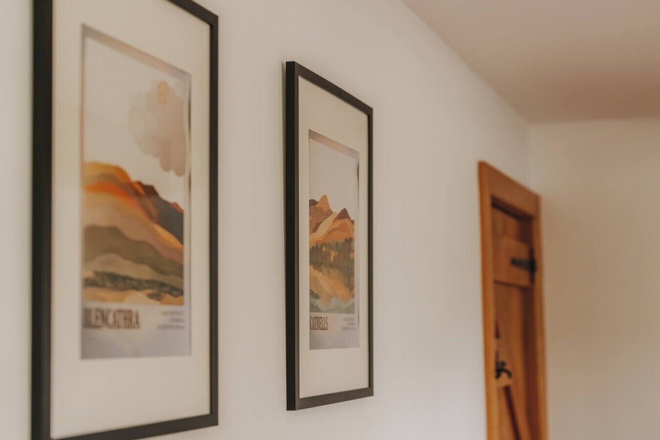 Framed artwork on a wall, a wooden door, and a white ceiling.