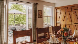 An open dining area with a view of greenery, wooden furniture, and a wall with a geometric pattern.