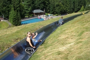 Una persona se desliza por un tobogán de metal, con una piscina al fondo.