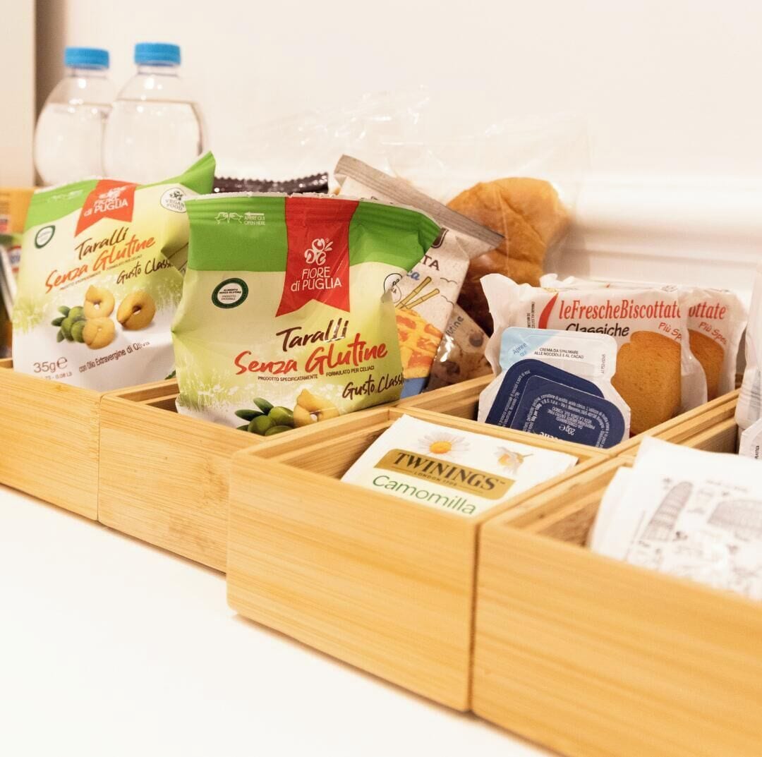 Un tiroir en bois contenant divers produits alimentaires, notamment des Taralli sans gluten, du thé à la camomille de la marque Twinings et des biscuits secs de la marque leFresche.