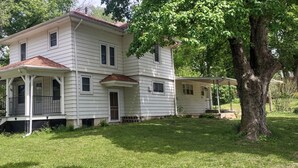 Ein zweistöckiges Haus mit Veranda, überdachter Eingangstür und einer kleinen angeschlossenen Garage.