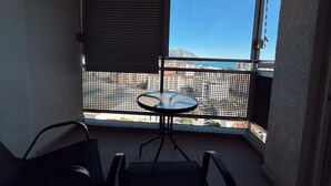 A balcony with a table and chairs, a view of a cityscape, and a mountain in the distance. - Sky and Sea View Apartment in Budva (Budva)