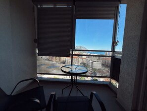 Ein Balkon mit Tisch und Stühlen, Blick auf eine Stadtlandschaft und ein Berg in der Ferne.