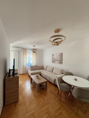 Ein modernes Wohnzimmer mit einer Couch, einem Couchtisch, einem Fernseher und einem Essbereich mit Stühlen.